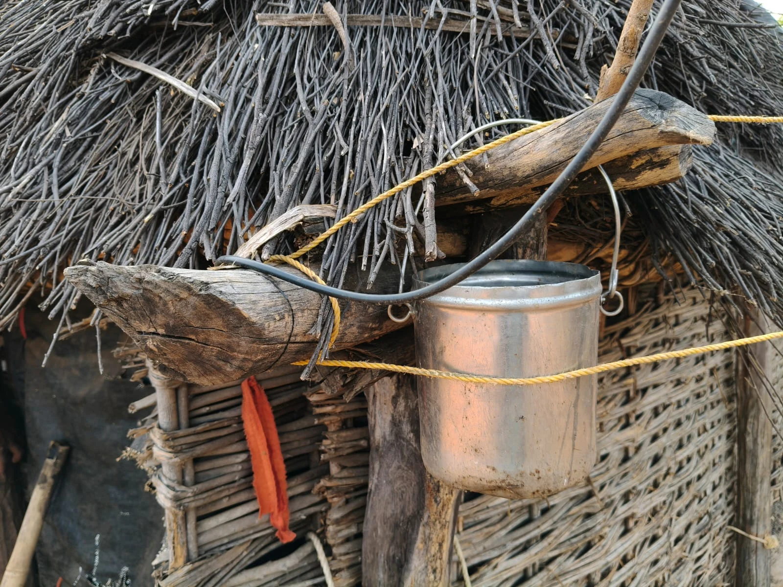A metal vessel hanging outside a hut.
