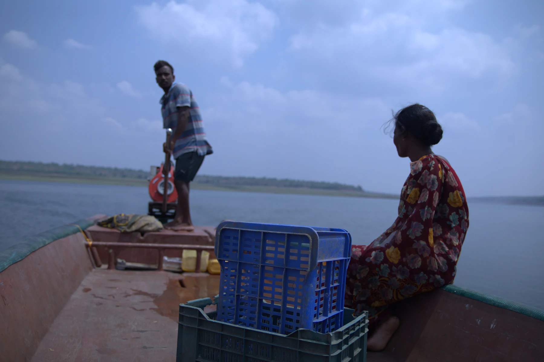 Two people travel across the river by boat.