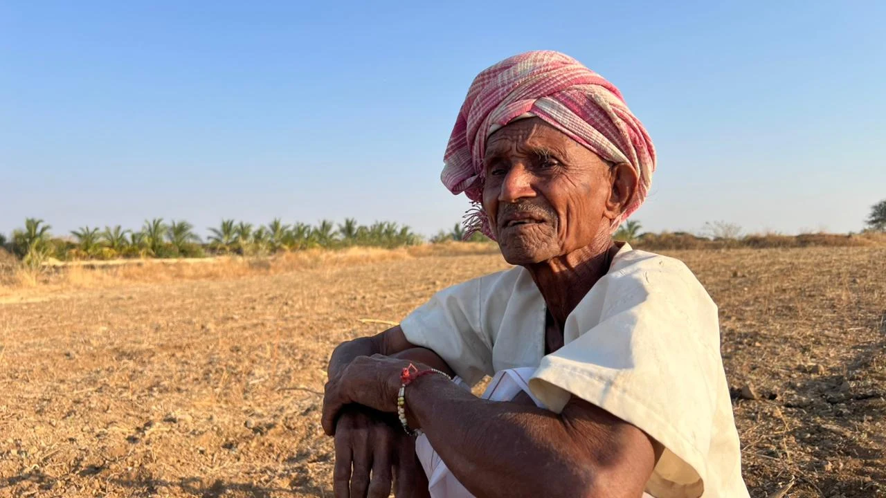 A shepherd sits in an open field.